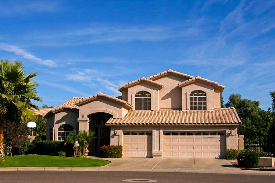 Two-story stucco home with fresh exterior paint, tile roof, and landscaped front yard